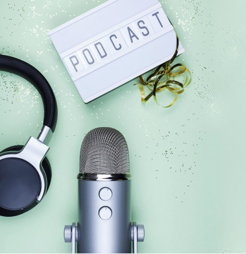 Microphone, headphones, and podcast sign on a green background.