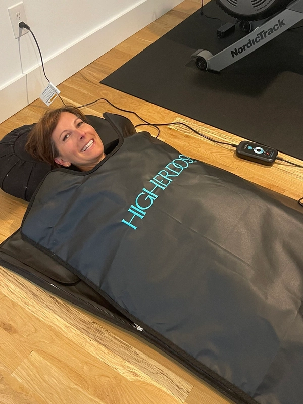 Person relaxing in a heated sleeping bag on a wooden floor.