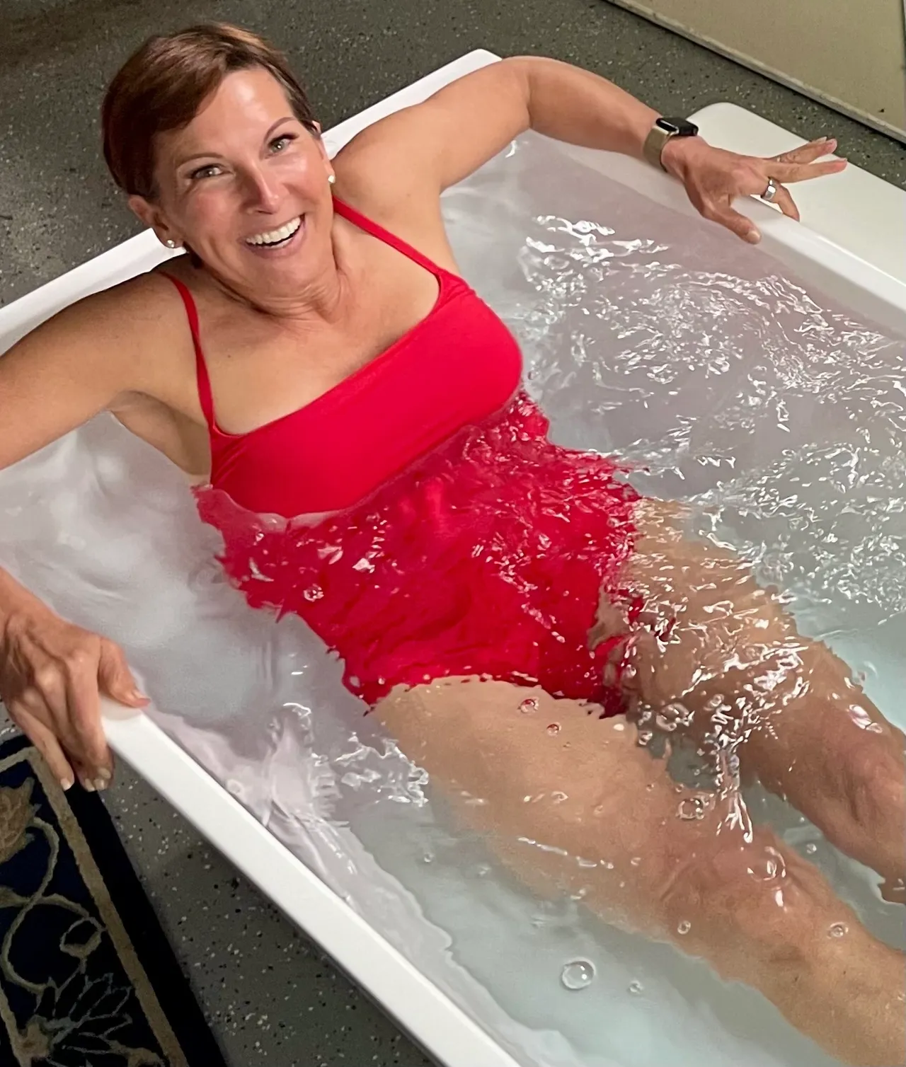 Woman in red dress enjoying a bath with water splashing.