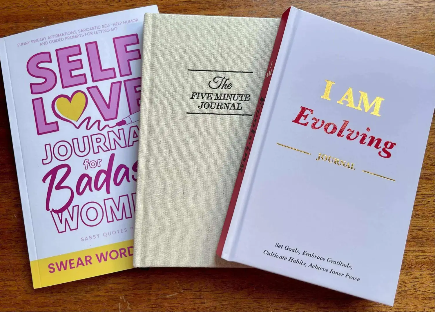 Three journals on a wooden table.