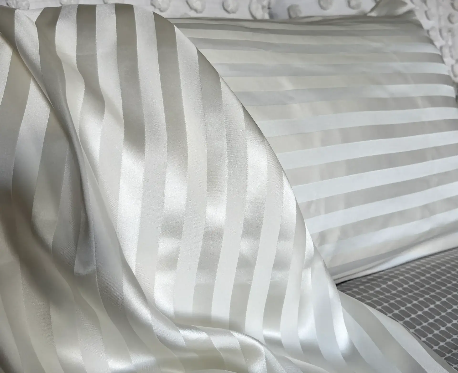 Striped white satin pillow and bedsheet.