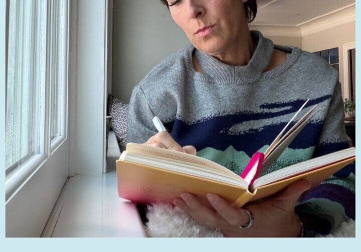 Author by a window journaling as one of three tools to find direction in midlife.