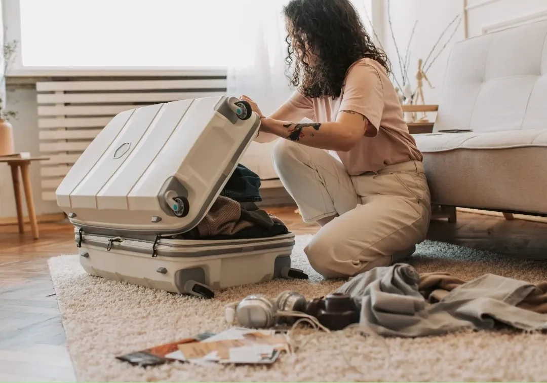 Woman packing a suitcase on the floor in a bright room.